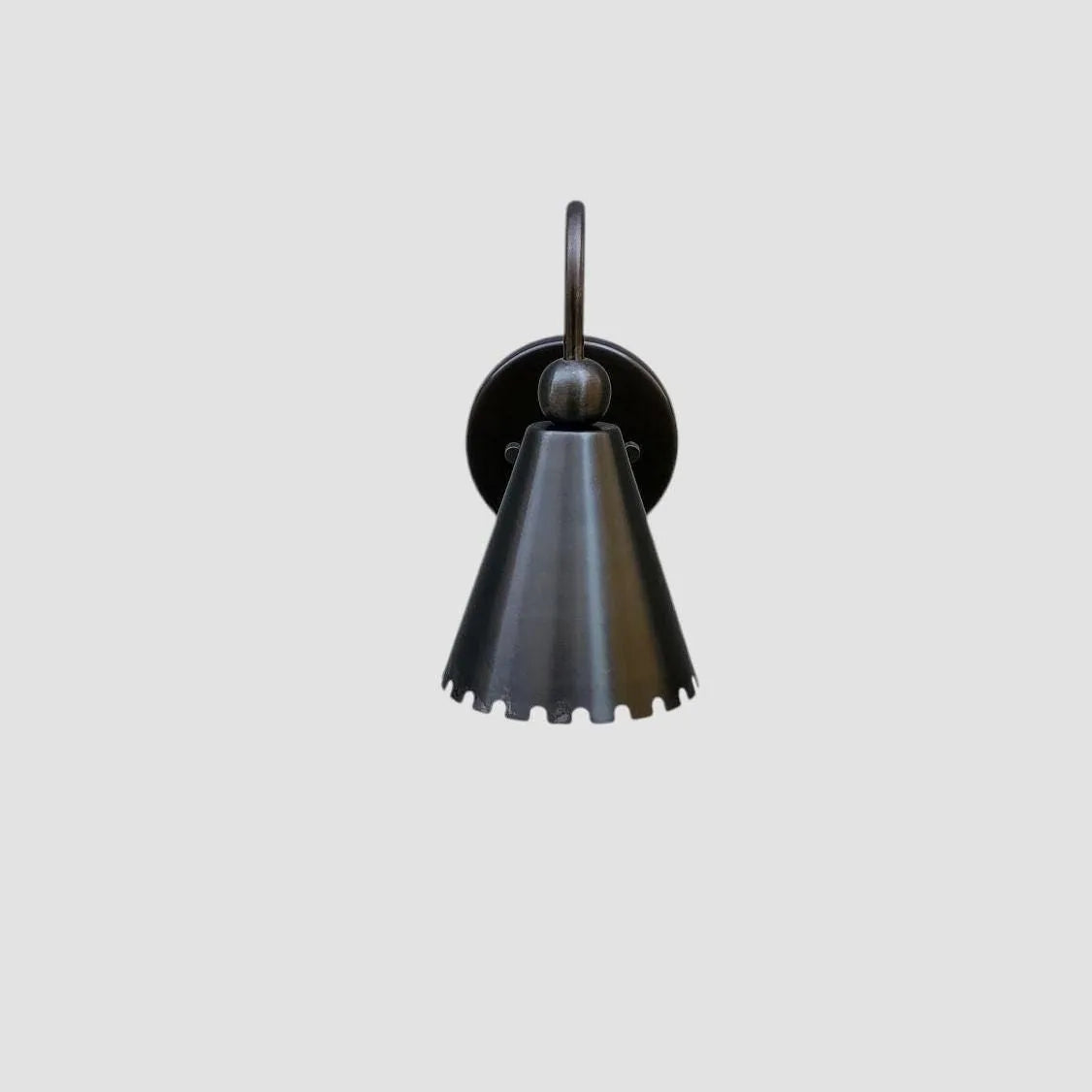 A single wall-mounted bell-shaped metal sconce in a dark gunmetal or black finish, shown against a solid light gray background.