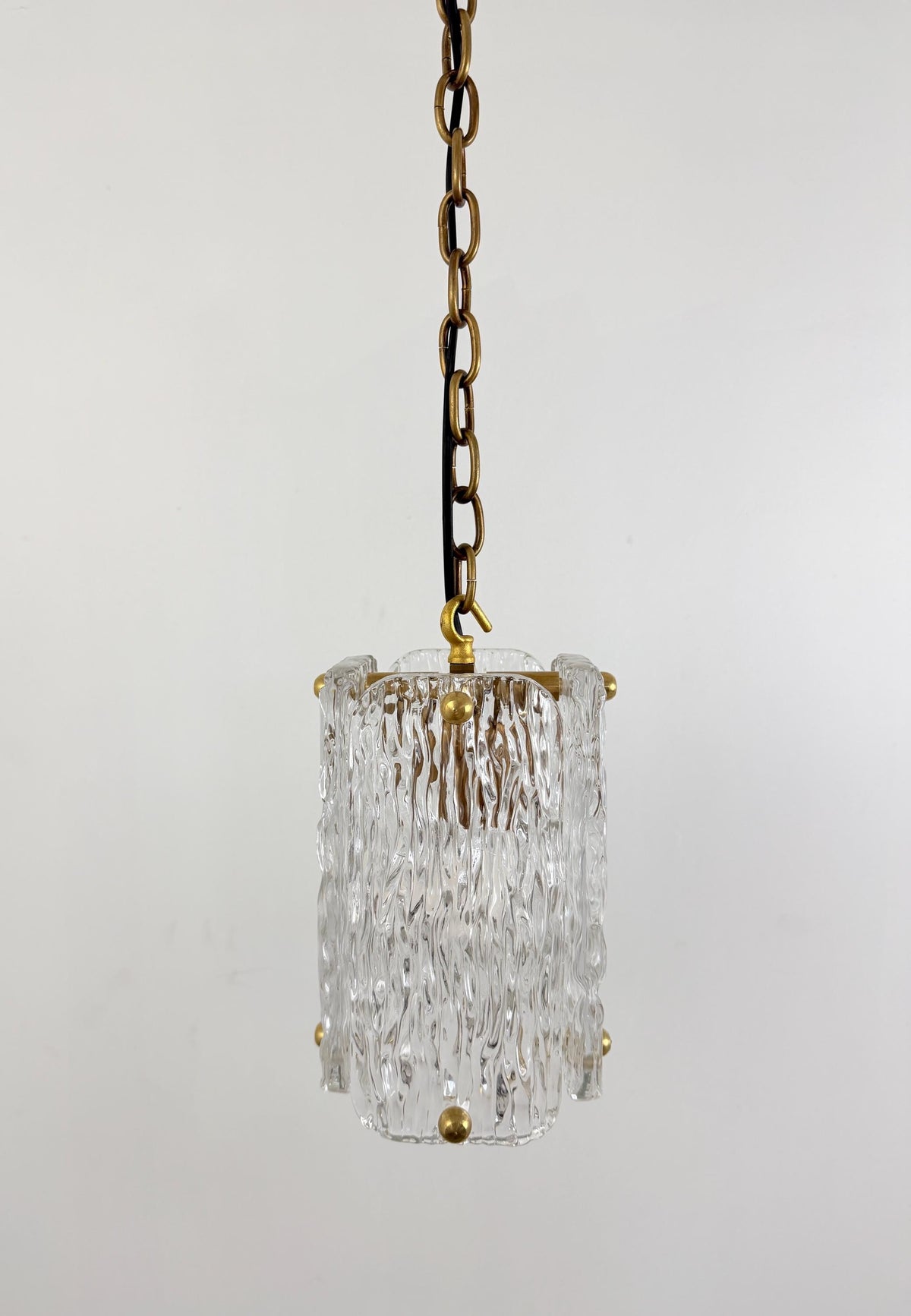 Clear textured glass hanging pendant light with polished brass hardware.