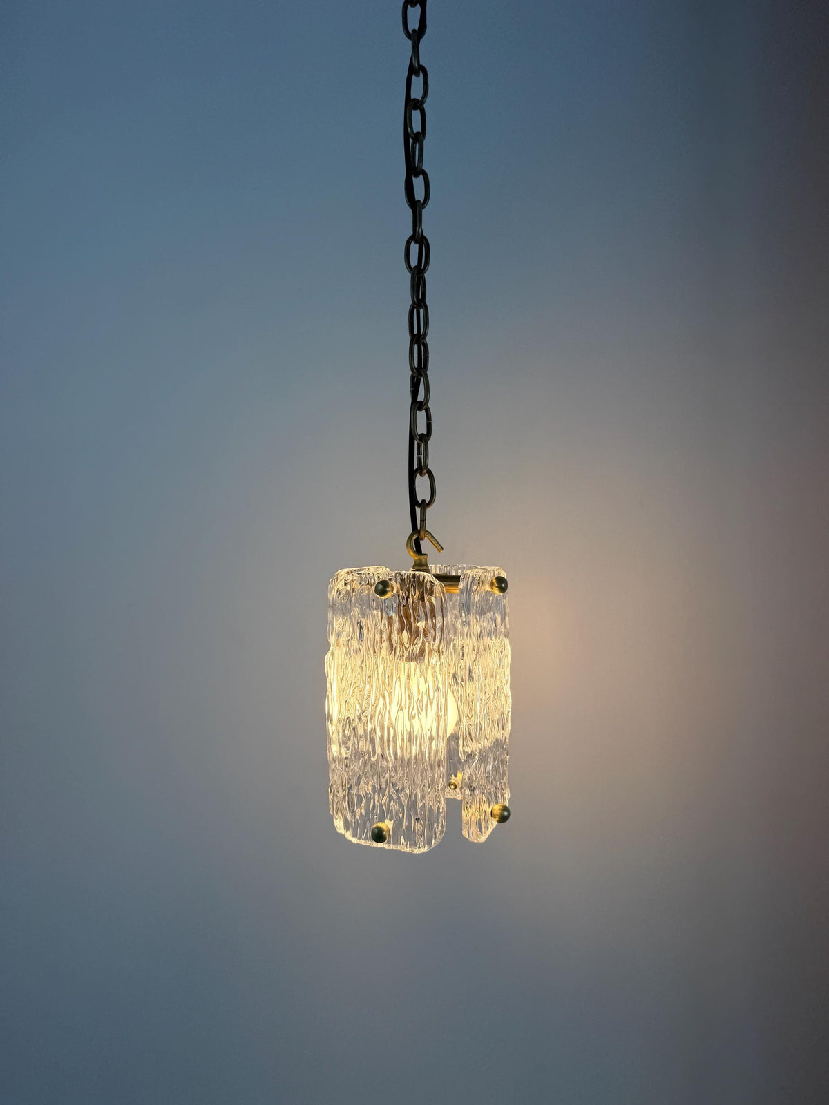 Elegant textured glass pendant lamp featuring brass details and chain hanging.