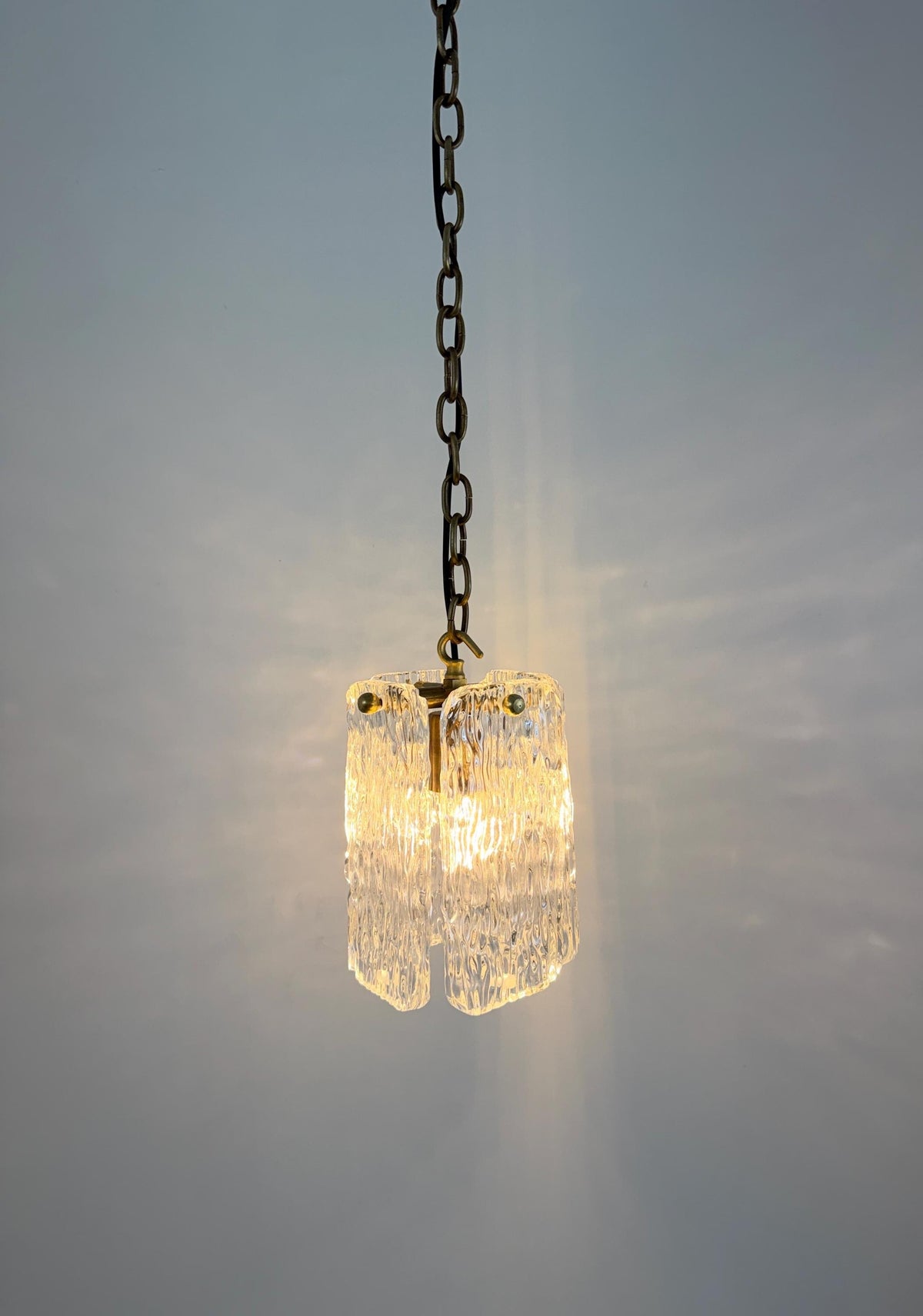 Frost Lights illuminated textured glass pendant light hanging down.