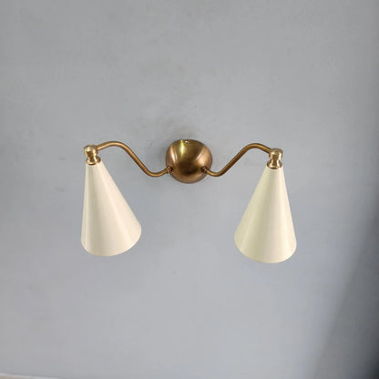Mid-century modern brass wall lamp with two conical white shades, mounted on a round brass backplate.