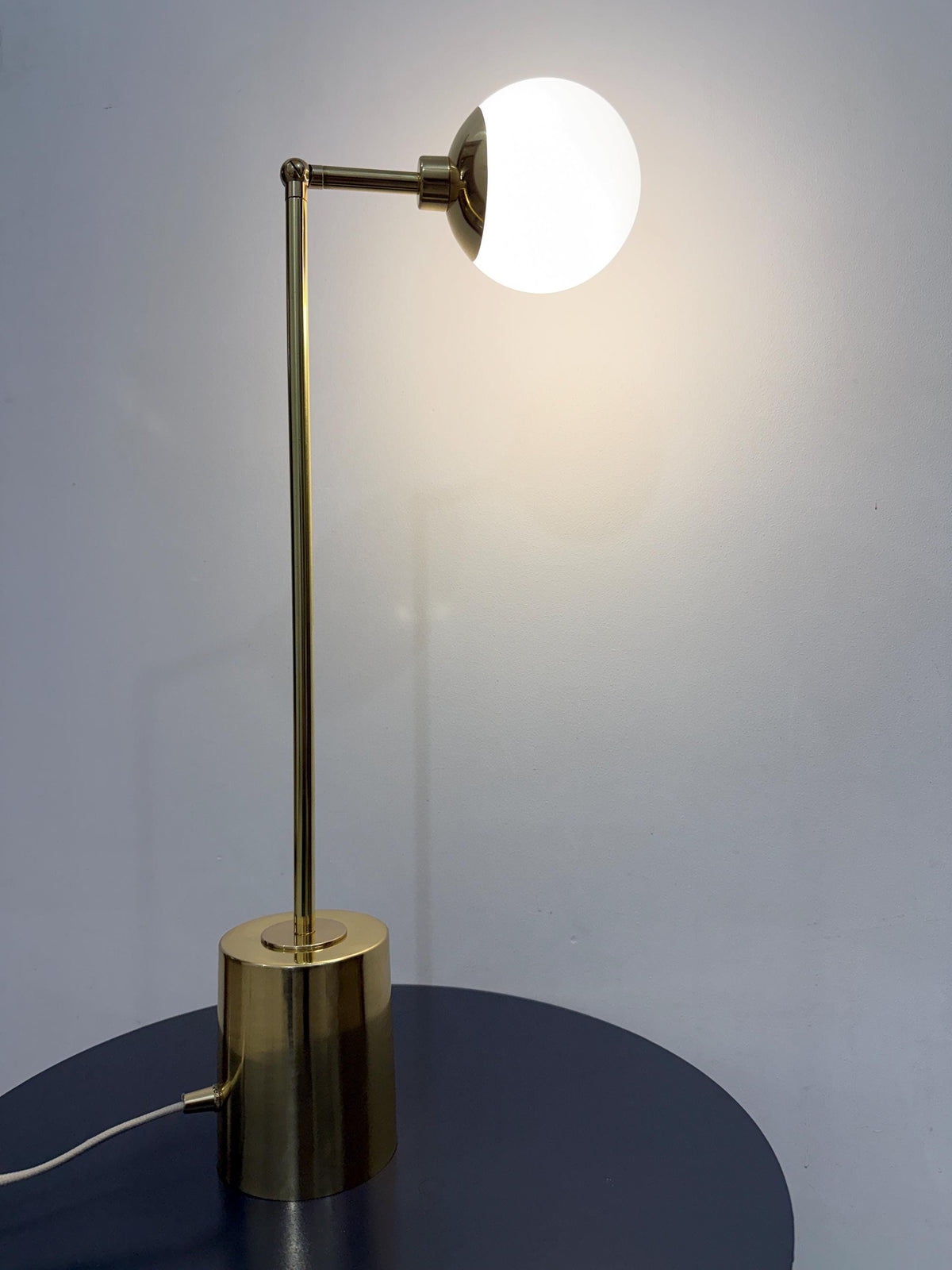 The Opal White Glass Globe Gives This Brass Table Lamp a Soft Rounded Focal Point, While the Adjustable Arm Adds Movement to The Otherwise Clean Silhouette. a Compact Cylindrical Base Supports the Handmade Fixture on Desks, Consoles, and Bedside Tables, Frost Lights.
