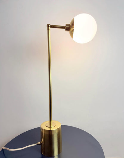 A Handmade Brass Table Lamp with A Slim Vertical Stem, Adjustable Articulating Arm, and Softly Rounded Opal White Globe Shade, Standing on A Compact Cylindrical Base. the Simple Silhouette Suits Bedside Tables, Desks, and Minimalist Interiors, Frost Lights.