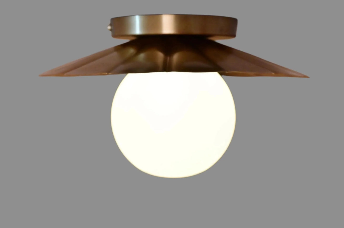Vintage brass chandelier with a floral design, featuring a white glass globe and a sleek, elegant silhouette.