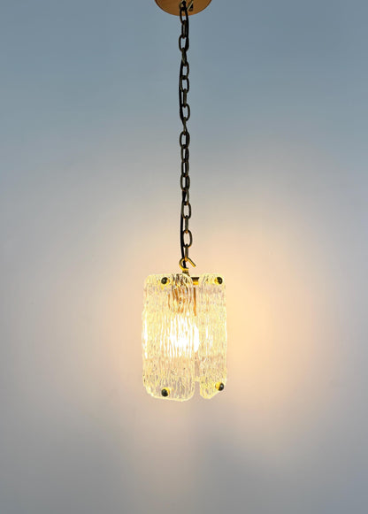 Textured glass lantern-style pendant light with brass details for home interiors.