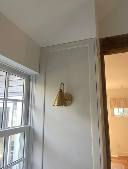 Timeless antique brass sconce with intricate detailing, enhancing the ambiance of a vintage-styled bedroom.